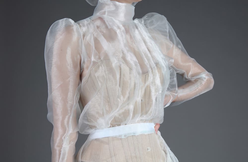 Detail of Evie Bertram's costume, showing the white frill of the neck and corset underneath.
