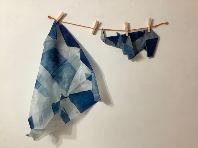 Origami rhino and piece of blue tissue paper hanging up on a drying line