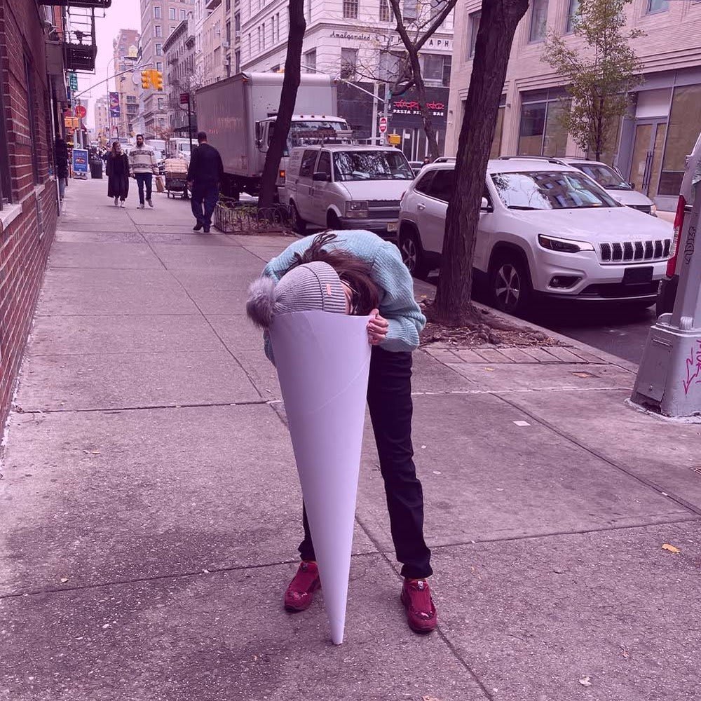 A picture containing outdoor, ground, way, sidewalk. A person leaning against a white cylinder