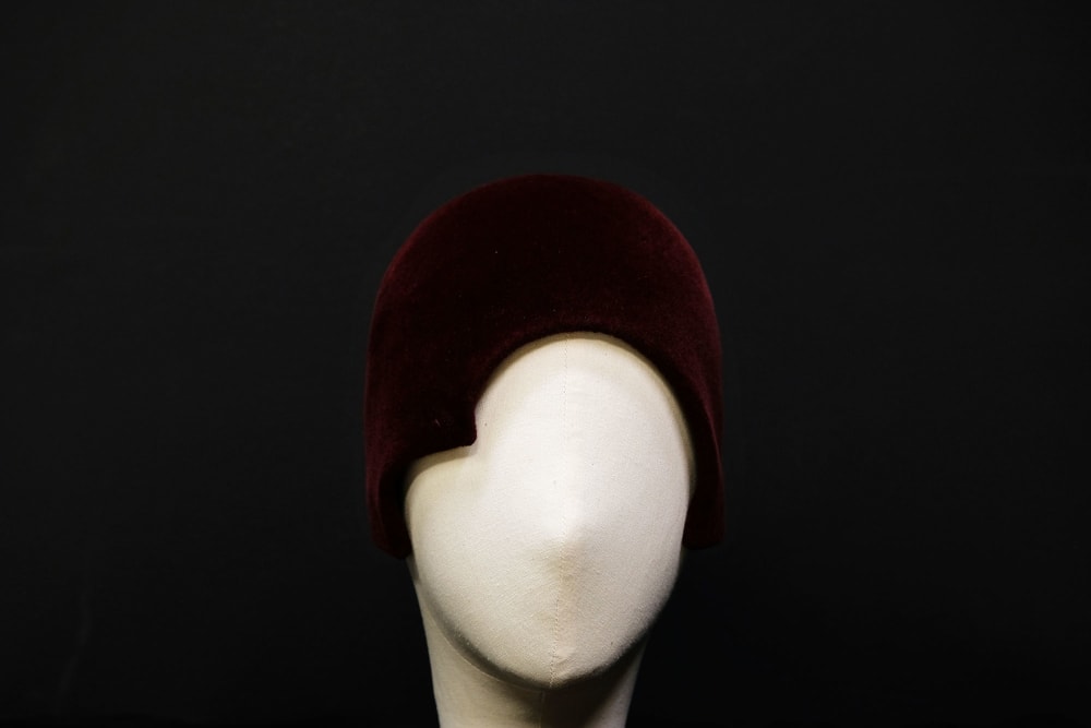 A mannequin head wearing red velvet head piece.