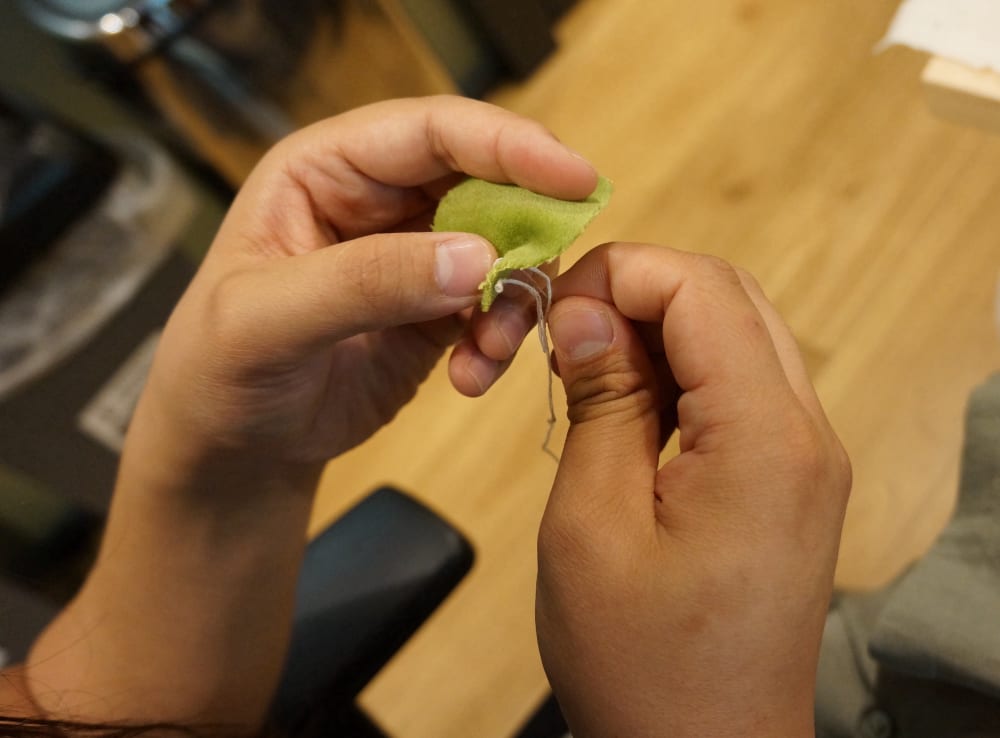 hands stitching green material