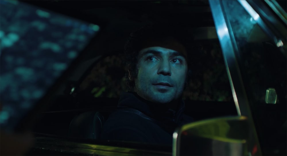 Film still of a person staring out of a car window.