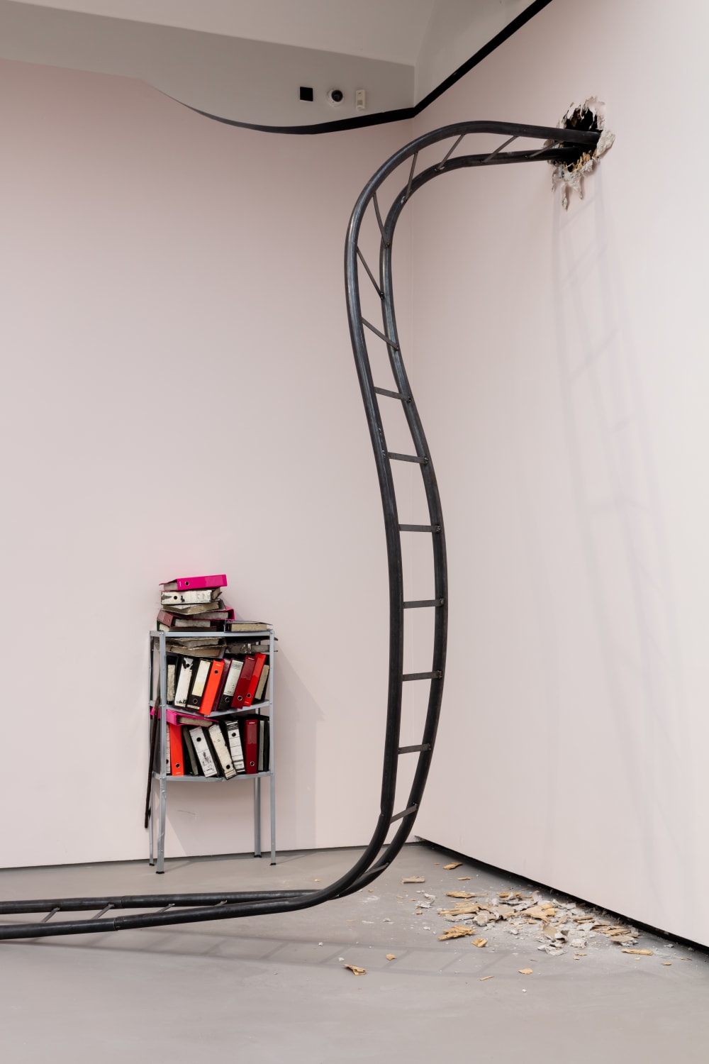 Close-up of steel rollercoaster coming out of the wall. With office files on shelves in the background