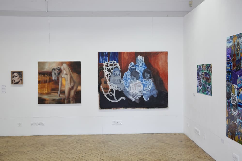 An installation shot of 5 canvases on the walls. One painting shows a naked woman slouched over, while the one next to it has 4 blue children painted