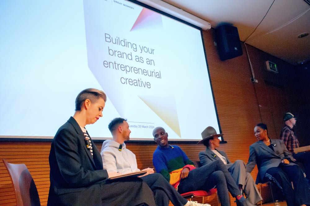 The panel sat preparing ahead of the talk. On the wall behind it says 'Building your brand as an entrepreneur creative