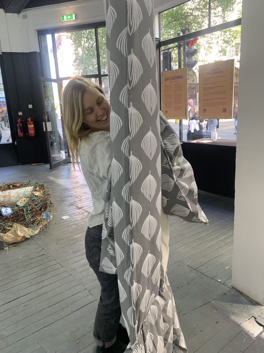 a person standing next to their work of fabric hanging out of the ceiling