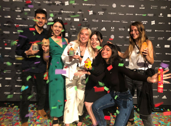 Six people celebrating with confetti holding trophies.