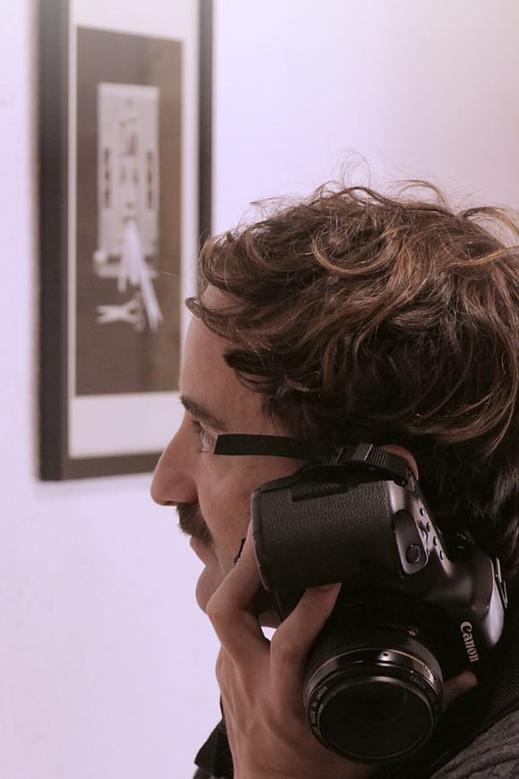 A man holds a camera to the side of his head