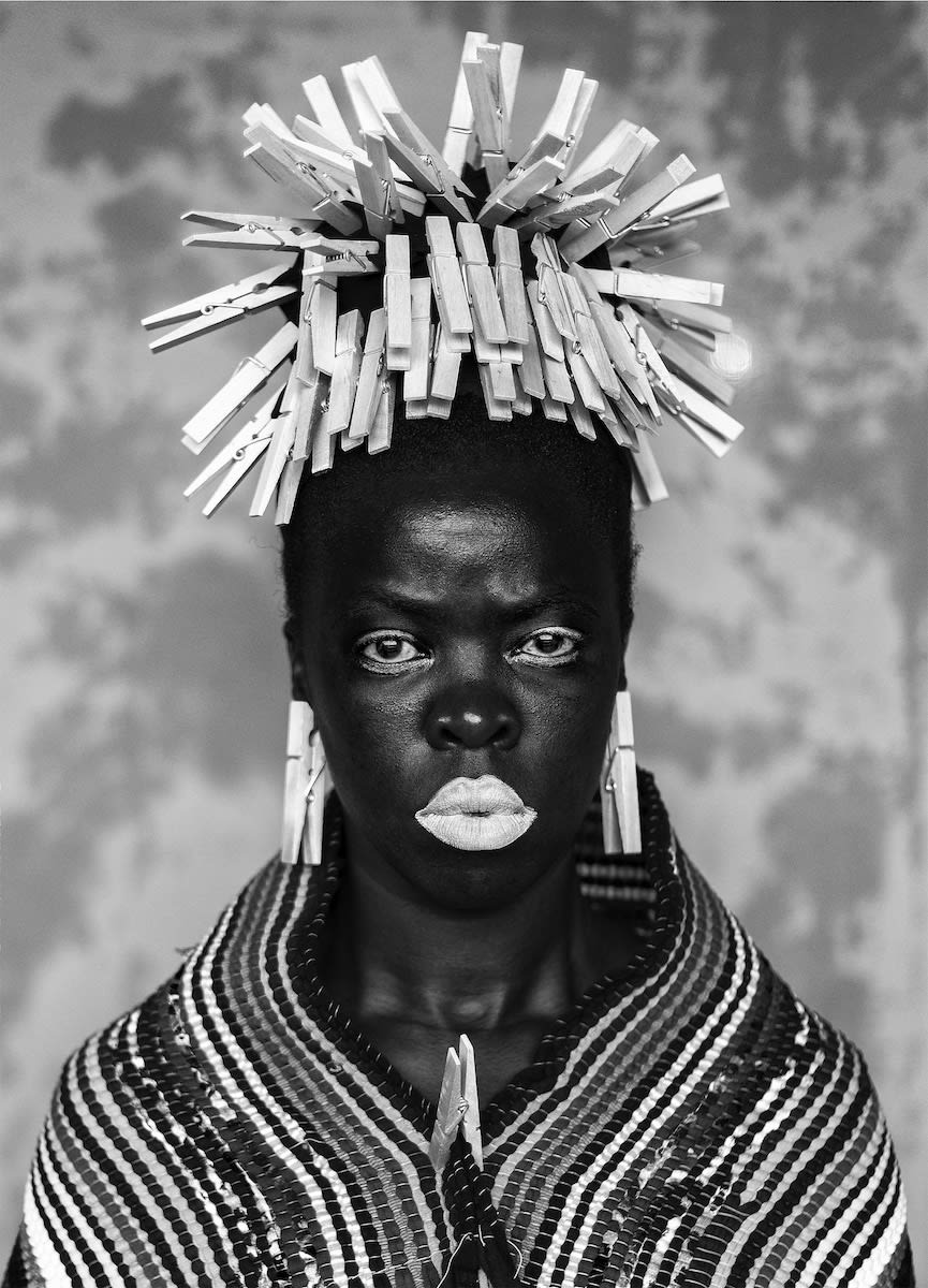 a black and white portrait of a women wearing a headdress made from clothes pegs