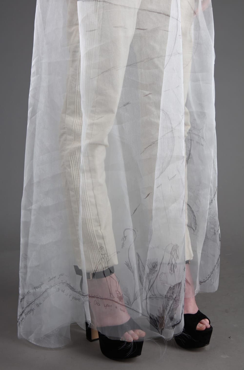 Detail of hem of dress and trousers can be seen underneath