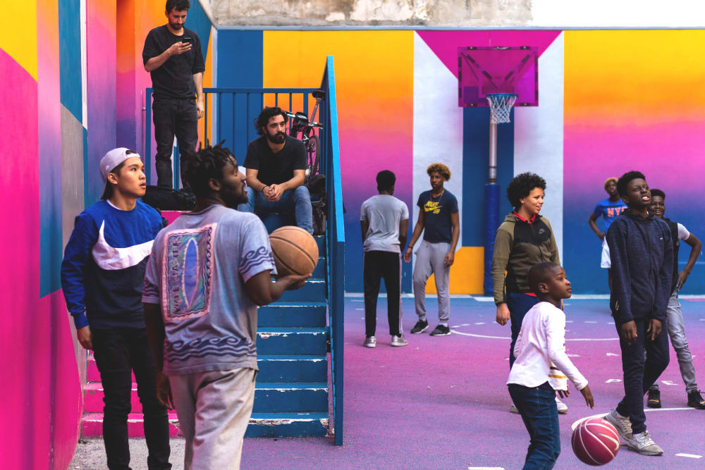 a group of people playing basketball in a colourful purple and orange court