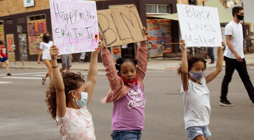 3 young girls marching with placards