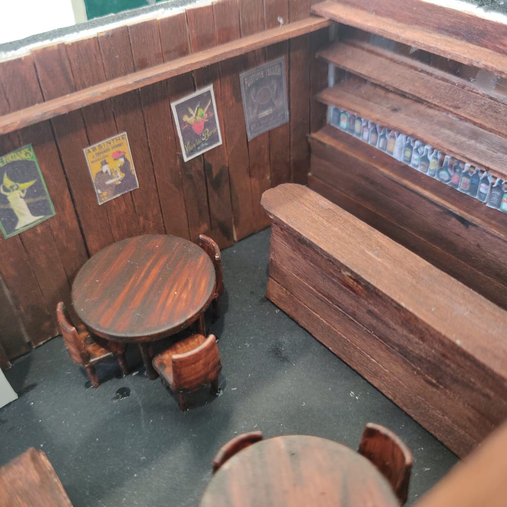 Pub set - A wooden bar, benches, and tables. There are artwork posters on the wall.  