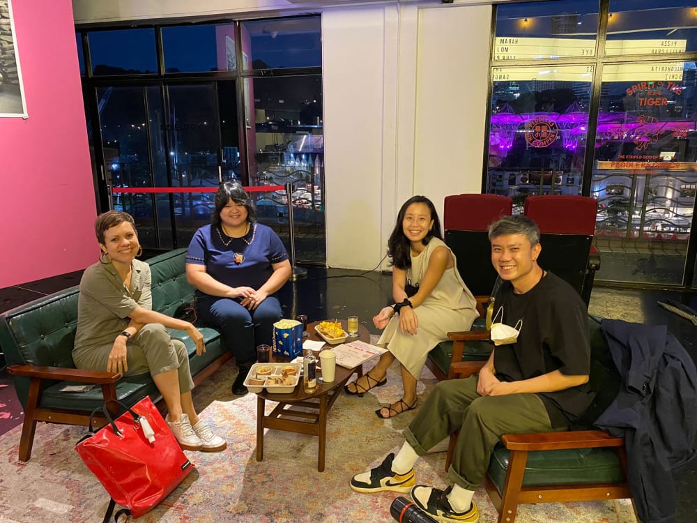 Four people sat around a coffee table, smiling at the camera. 