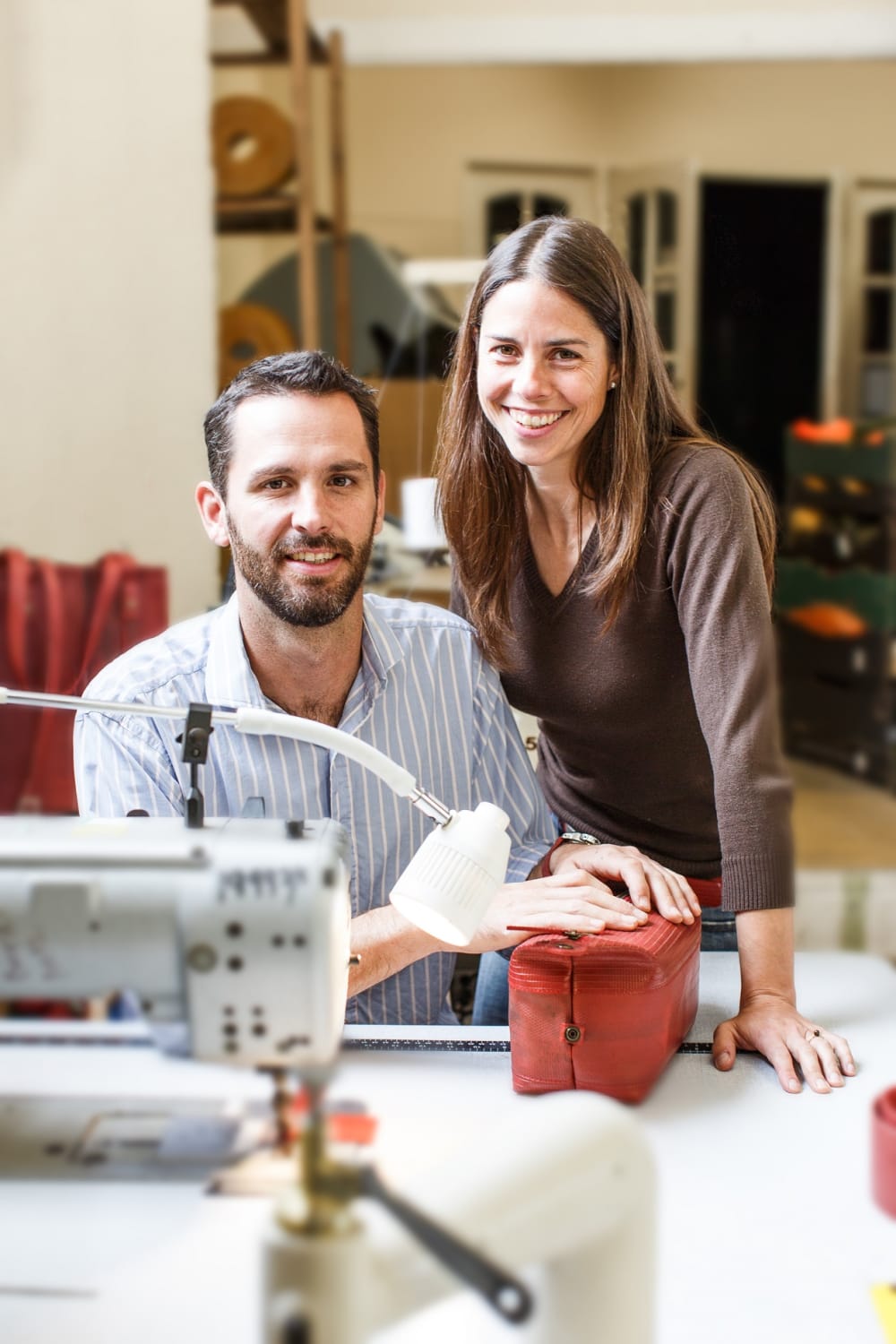 Elvis and Kresse posing for a portrait in their studio with a sewing machine in front of them