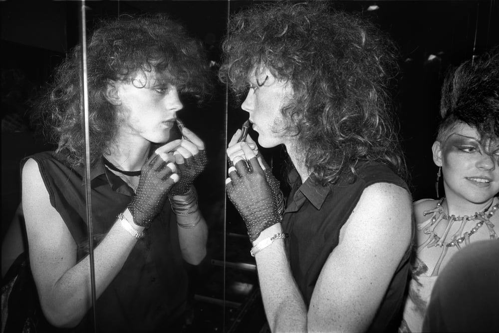 a black and white photograph of a person looking in the mirror as they are applying lipstick