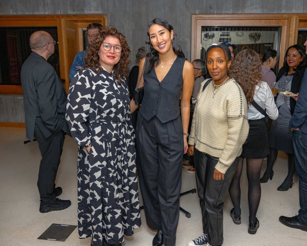 Guests at the reception smiling at the camera. Behind them, people are stood chatting