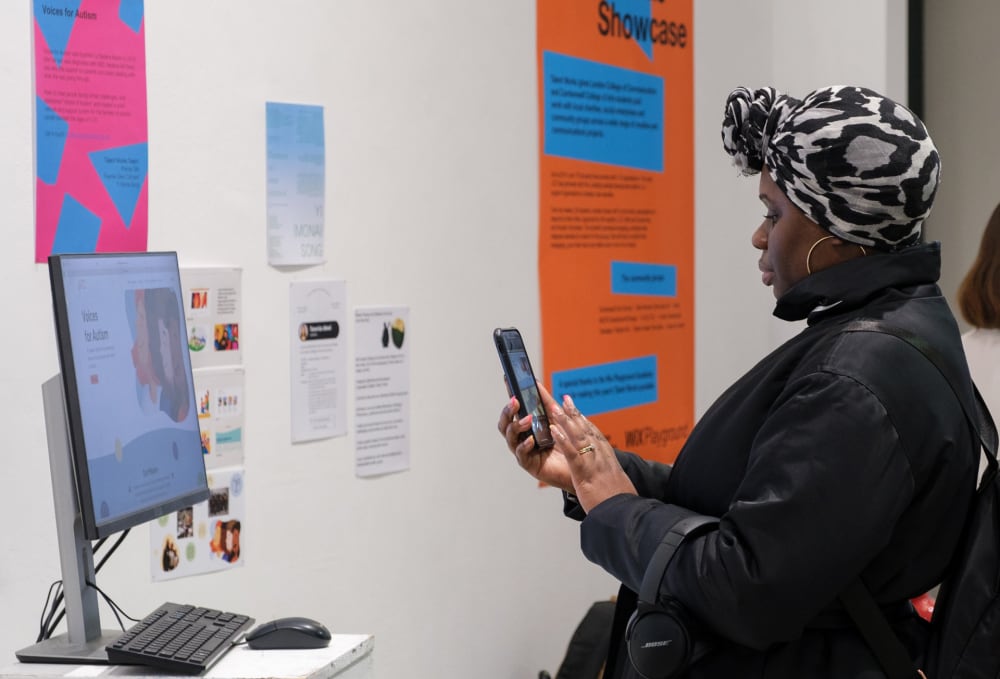 Woman taking photo of a computer screen with a new website page designed by the LCC team.