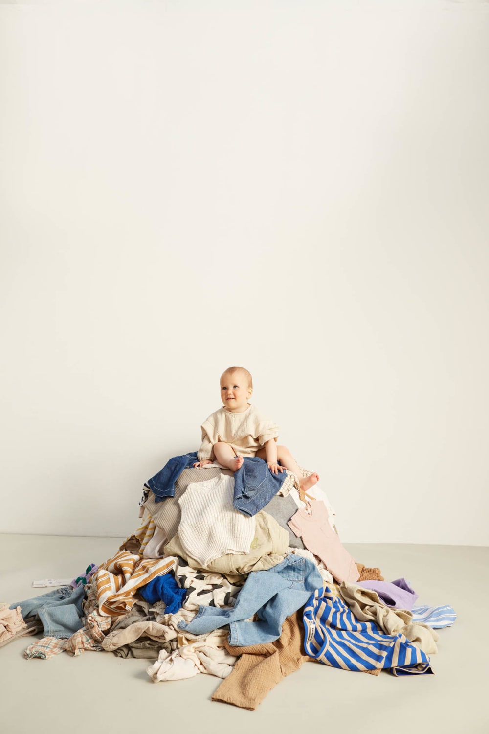 A baby sitting on top of a pile of clothing