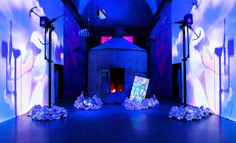 A photo of Heather Phillipson installation in a blue and purple room