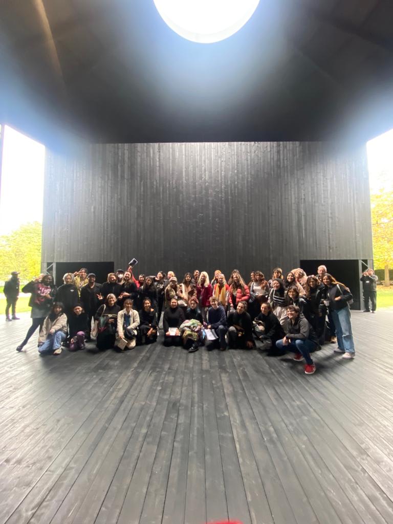 A photograph of a group of students in a dark wooden room