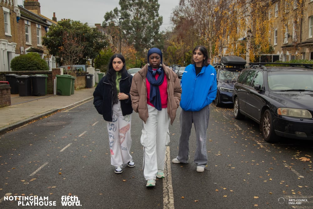 Three young women standing on a residential street.