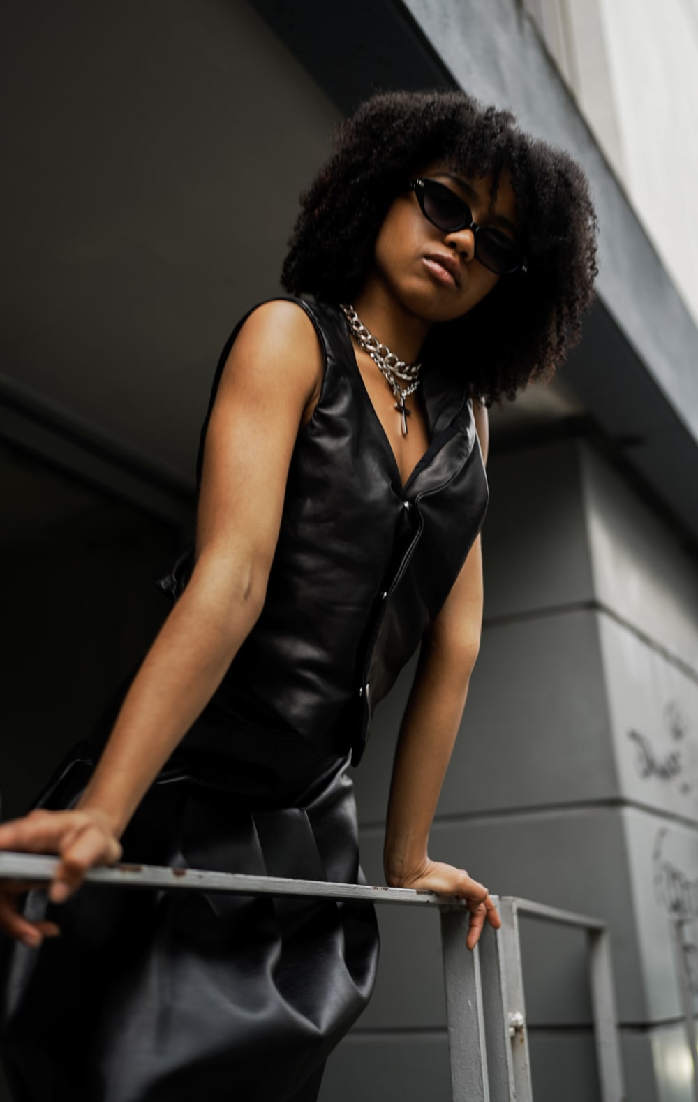 Model leaning over a balcony wearing a black vest.