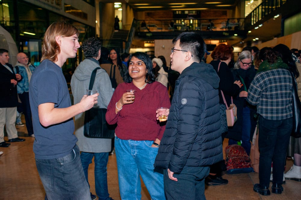 Three people chatting, behind them are other guests