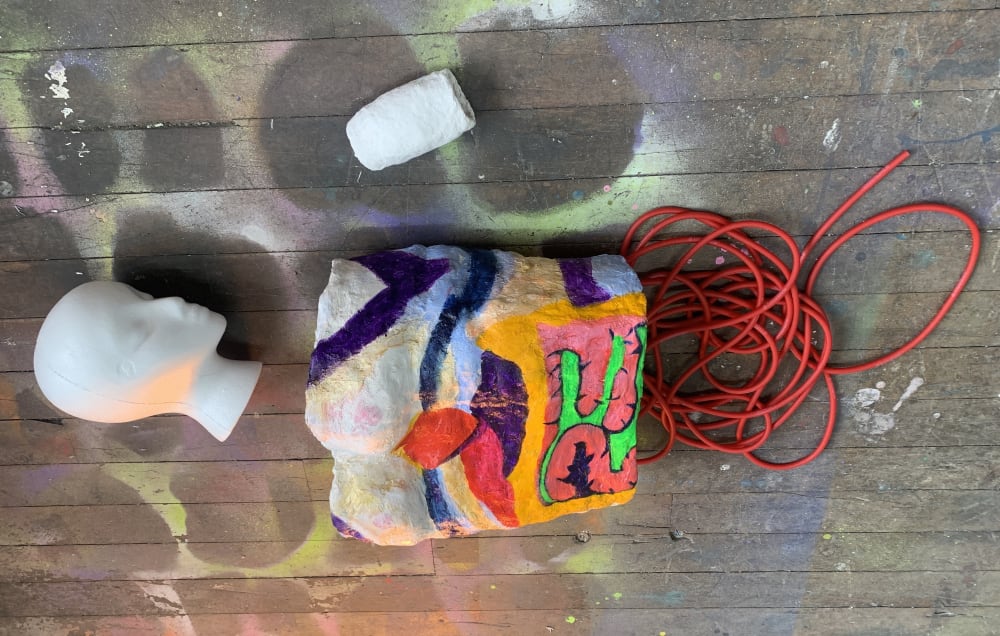 Work in progress of a polystyrene head, painted block and red plastic tubing. 