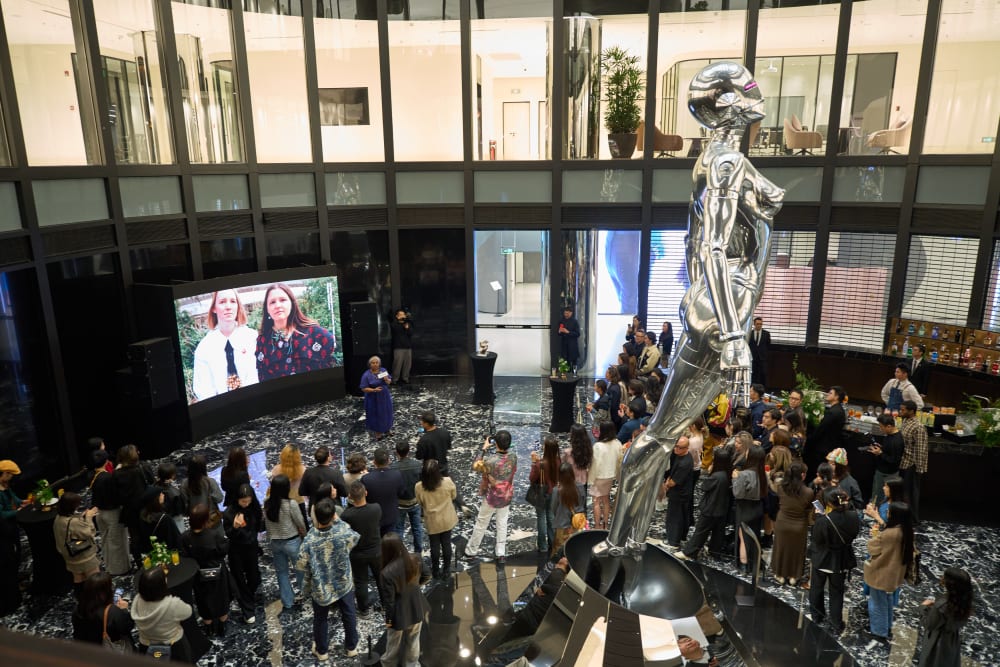 Photo from above of the guests, in the centre of the room is a huge silver sculpture of a female robot 