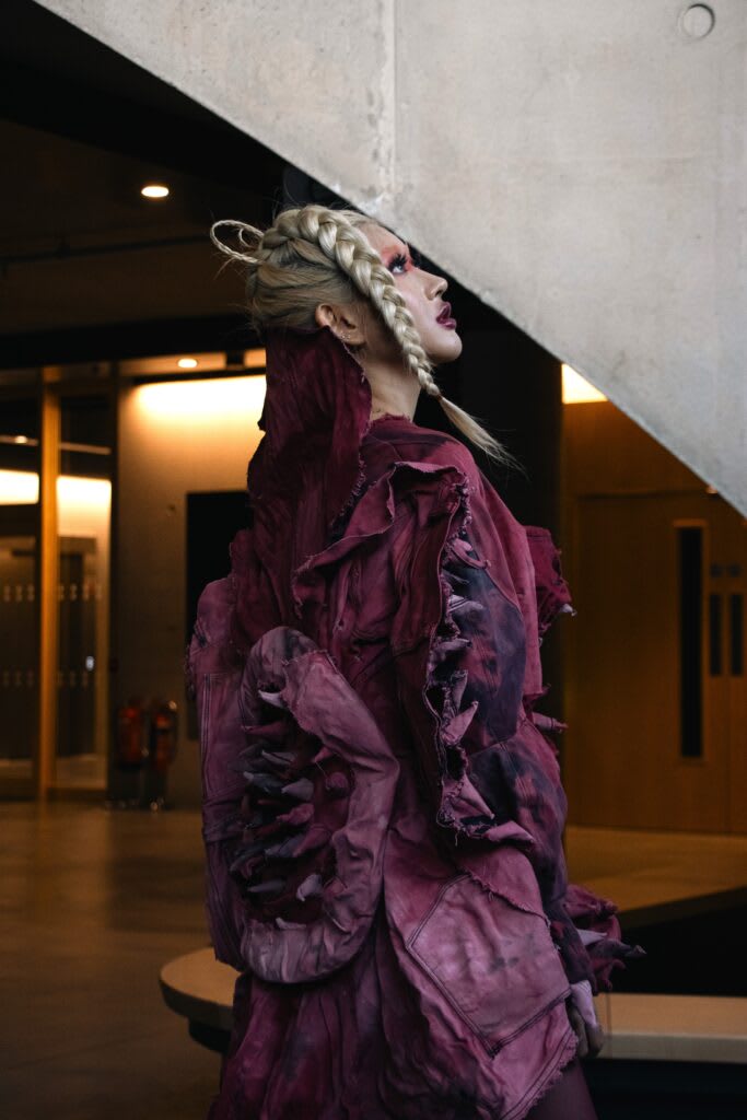 Person in maroon dress looking up at an angle. 