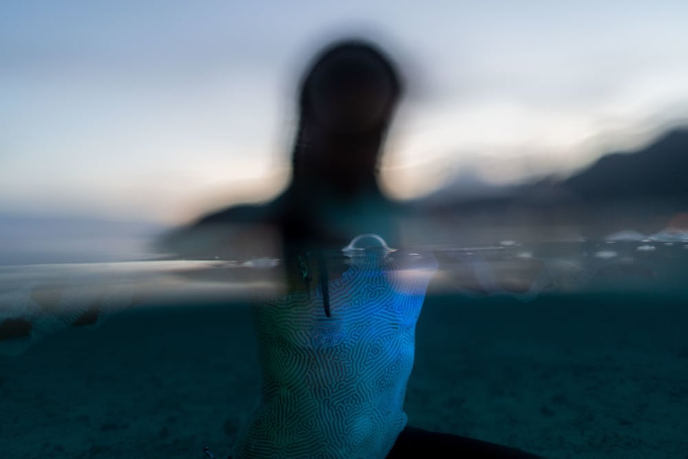A model in the water, wearing a blue swimsuit