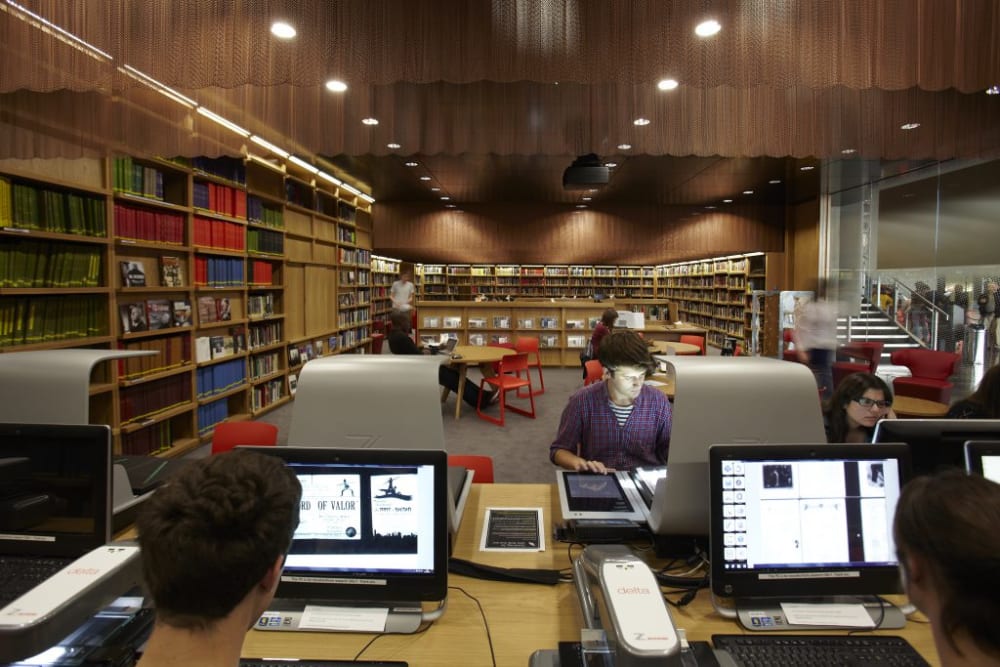 an image of a library, with people sitting at computers researching