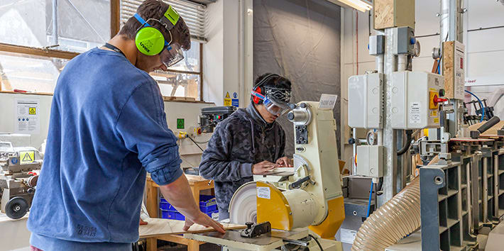 A pair of students using sanding machines.