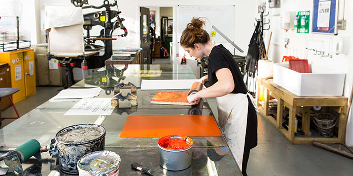 A technician preparing a monoprint in the Printmaking area.
