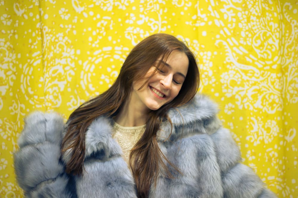 A person in blue coat standing in front of yellow background