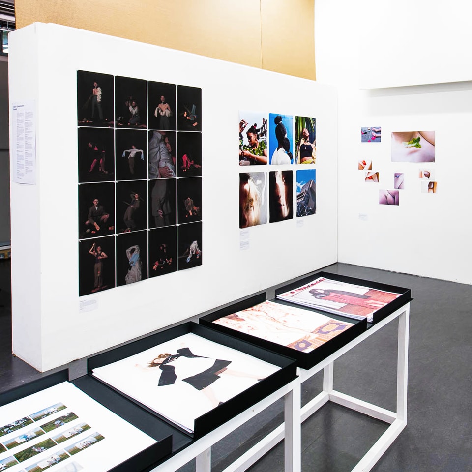 Student work is displayed at the pre-degree show on a white table and walls