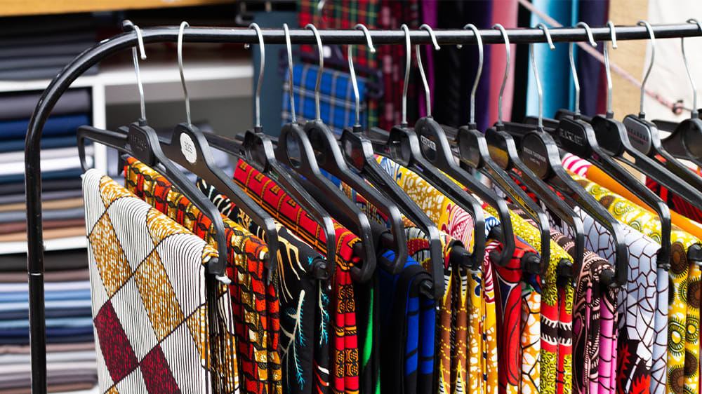 Colourful scarves hang on coat hangers at a stall in Shepherd's Bush Market