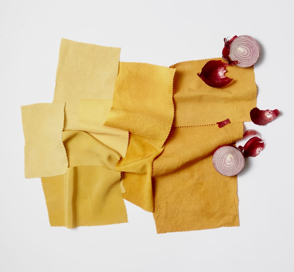 Fabric swatches layered on top of each other in various orange colours dyed by onions