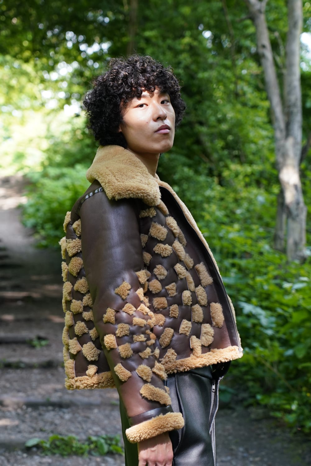 Model wearing faux brown leather jacket with faux wool and faux black leather pants