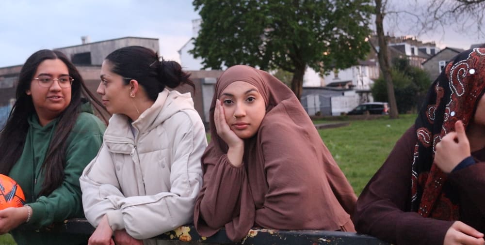 Three people, two of them talking and one looking at the camera.
