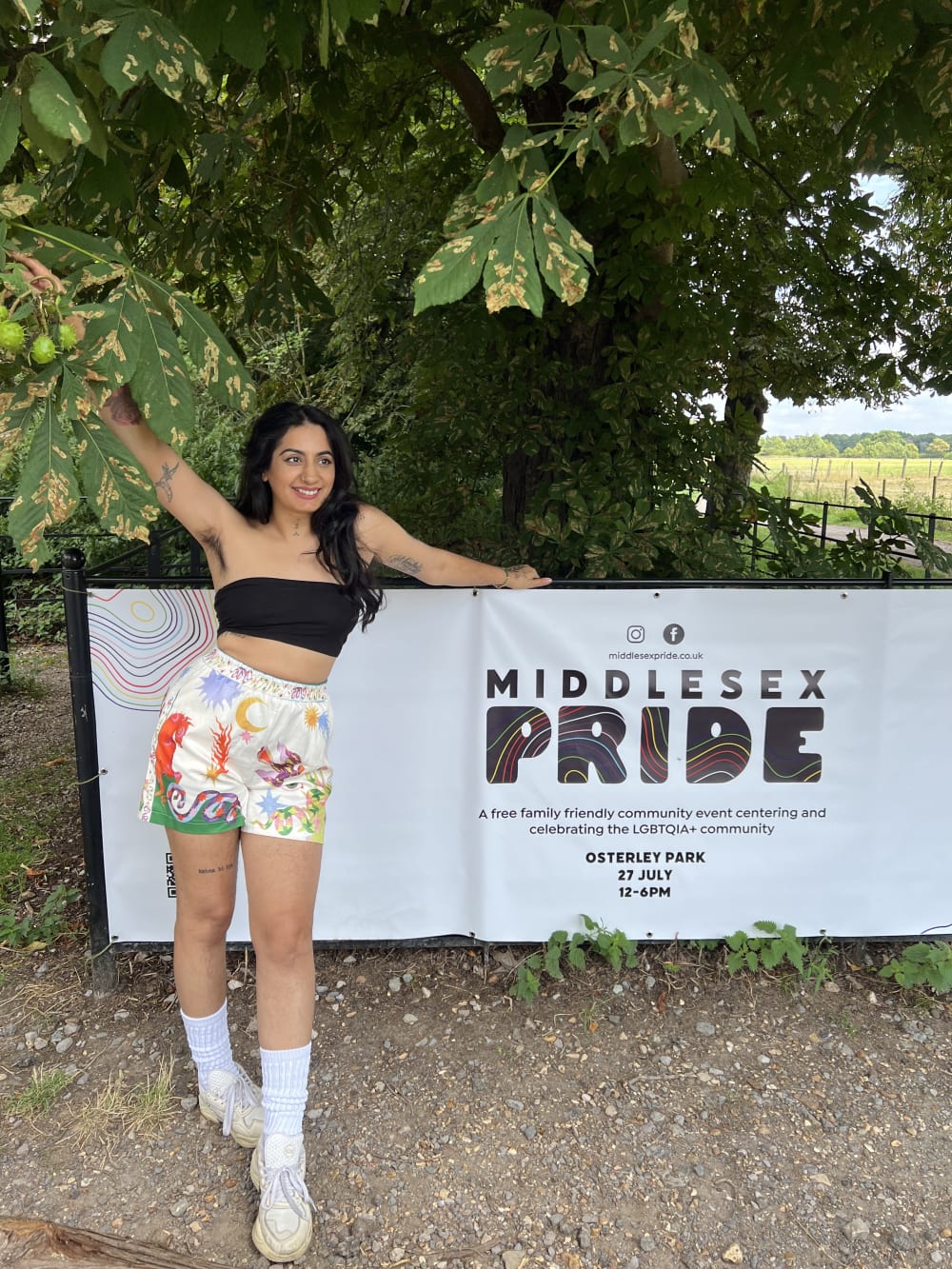 Sharan standing in front of a banner for Middlesex Pride