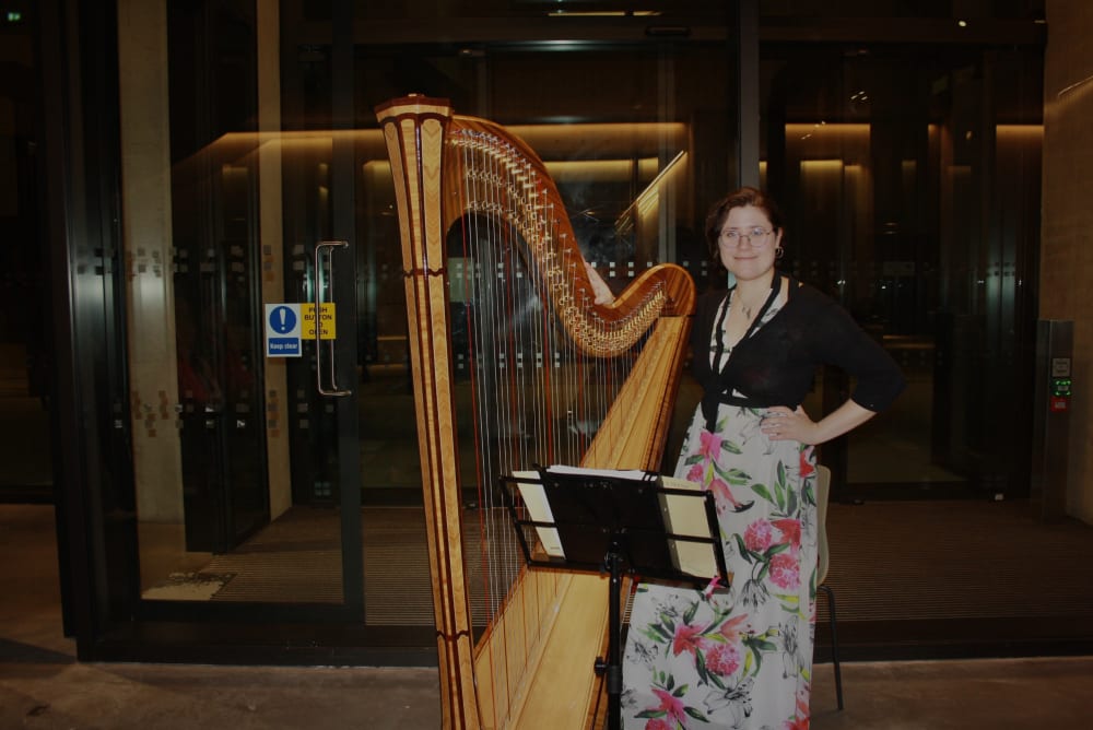 Person standing with a harp smiling at camera