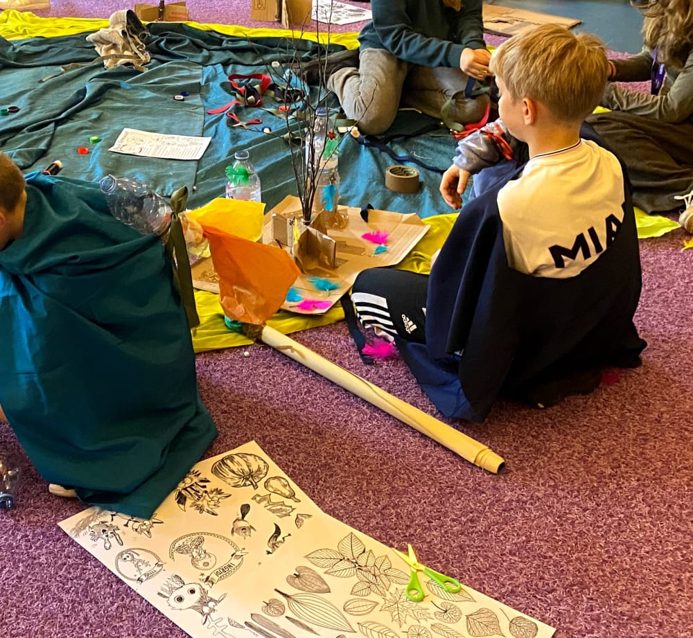 Group of children sitting on floor using arts and crafts materials.
