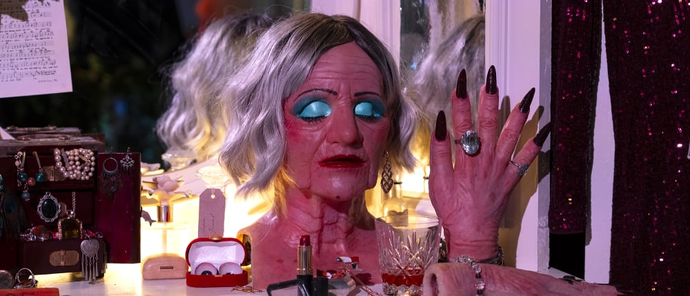 Prosthetic head of a an old lady with blue eye shadow.