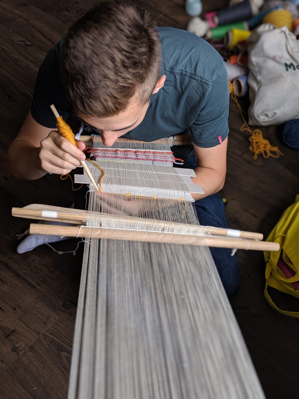 Member of the public backstrap loom weaving as part of sara kelly, ma textile design's workshop
