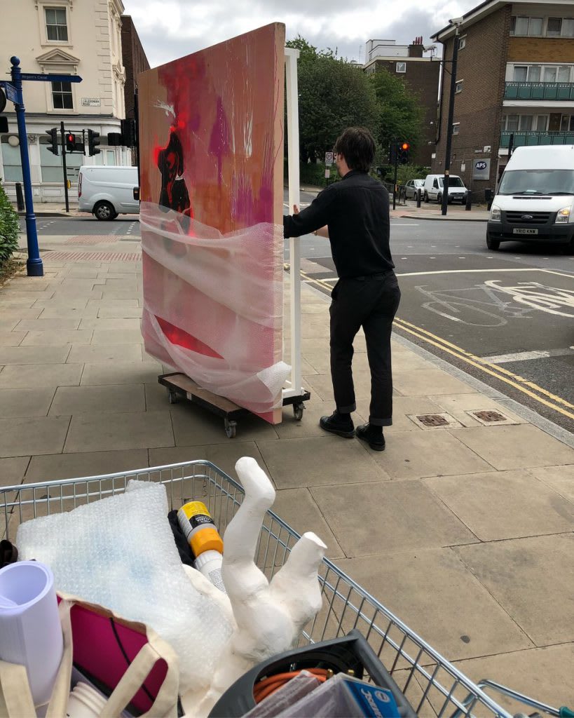 a photo of a person carrying several large canvas' on a platform with wheels