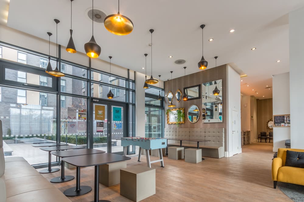 University halls common room with stone grey features, hanging lights and a foosball table