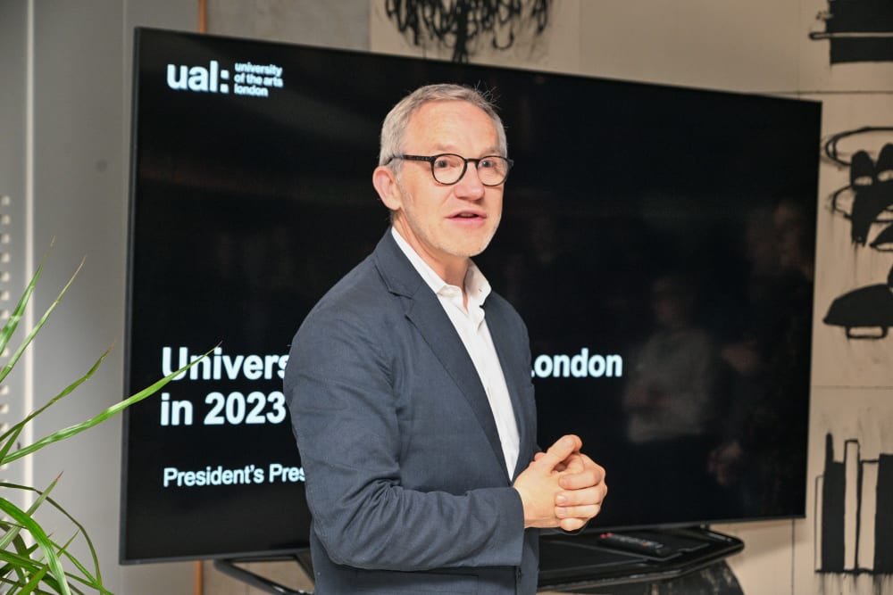 Close-up of James Purnell talking. He's stood in front a screen which reads: University of the Arts London in 2023, President's Presentations