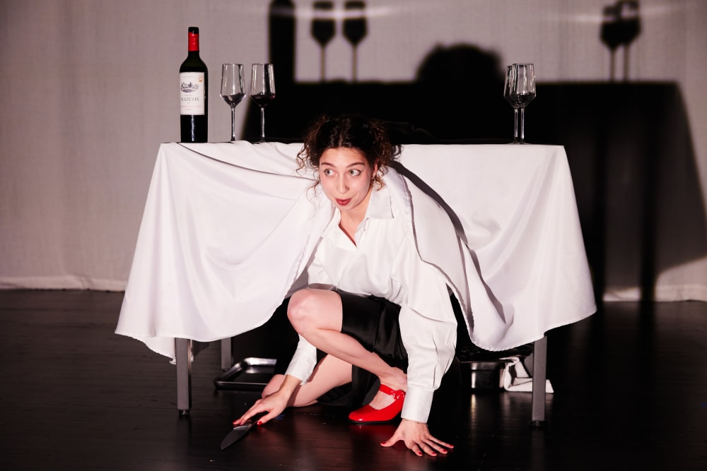 A woman giving a performance about being a waitress emerged from under a table with a knife